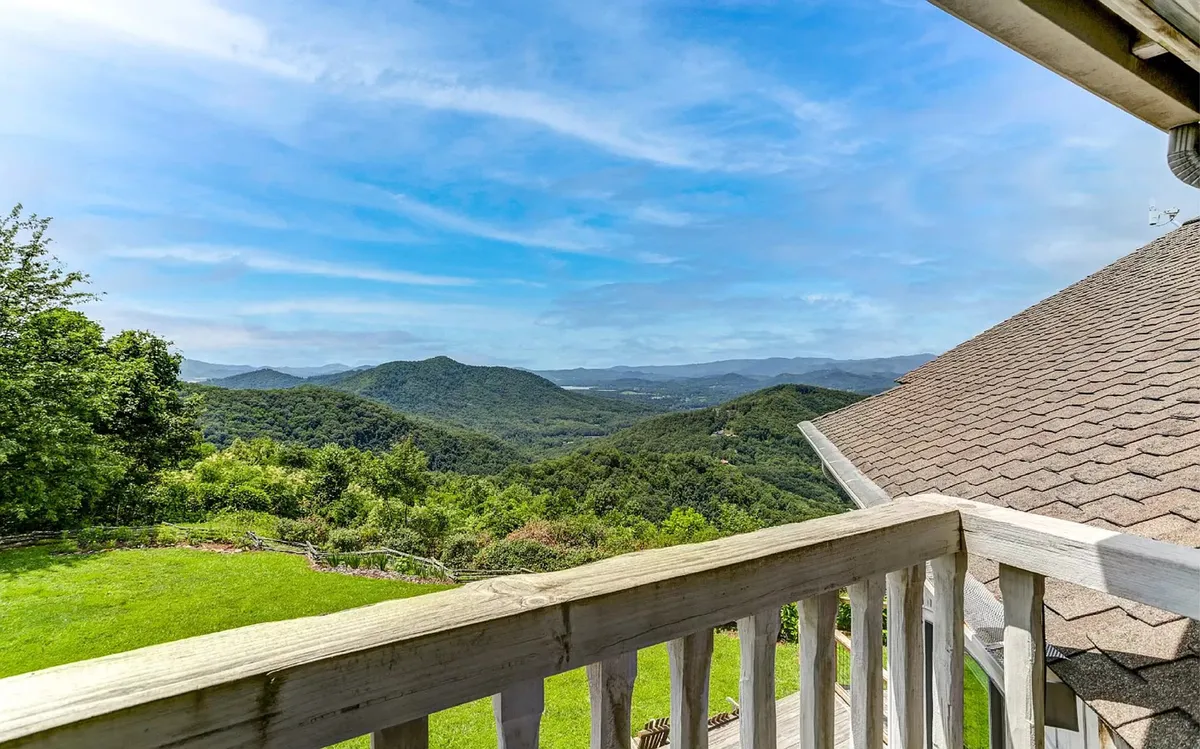 This image showcases a breathtaking mountain landscape, with lush greenery and a clear blue sky stretching above. The vantage point suggests a tranquil spot to enjoy a morning coffee or meditative reflection, perfectly capturing the serene beauty of the natural surroundings.