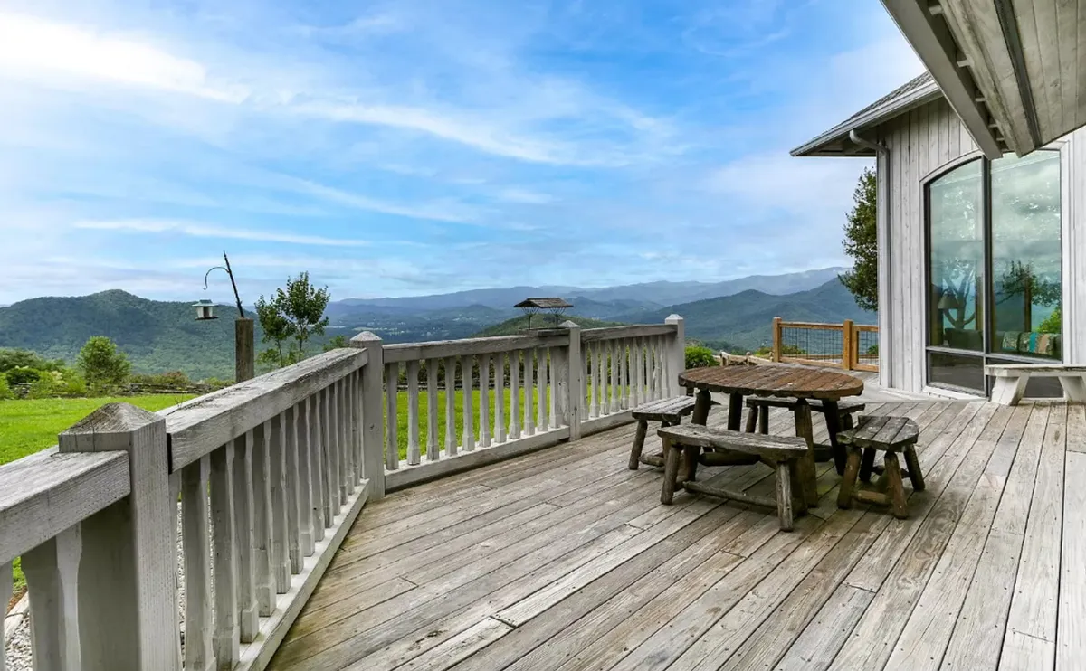 A serene wooden deck with an outdoor table faces a breathtaking mountain backdrop. The setting invites guests to enjoy meals, drinks, or quiet contemplation with nature all around, highlighting the estate’s privacy and scenic beauty.