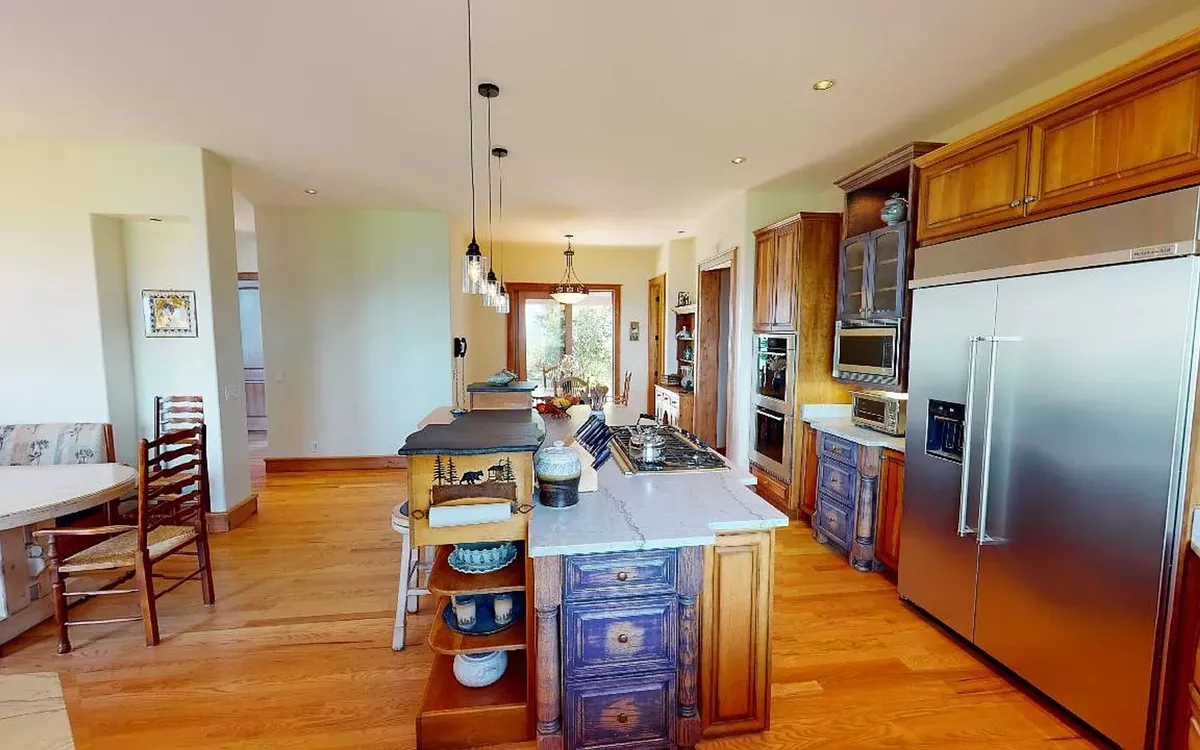 An open-concept kitchen with a generous island, high-end stainless steel appliances, double ovens, and a dining area seamlessly integrated for entertaining. Warm wood cabinetry and thoughtful design details create a space perfect for both preparing and enjoying meals with guests.