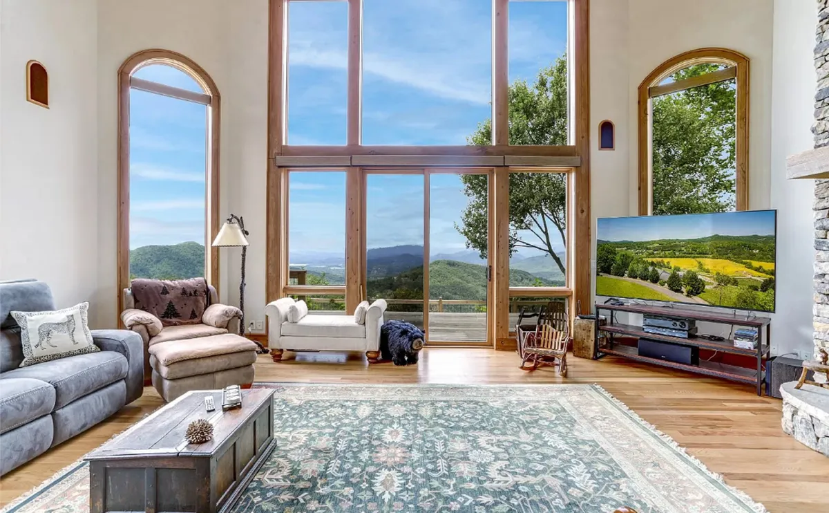 This cozy living space features large windows framing sweeping mountain views, comfortable seating, and a serene atmosphere. The room’s design draws attention to the surrounding landscape and hints at the home’s connection to the outdoors.