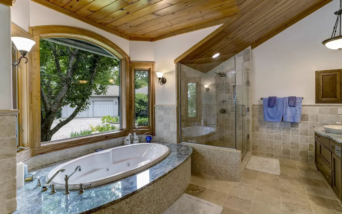 A spa-like bathroom featuring a freestanding bathtub, a glass shower, expansive windows with scenic views, and elegant finishes. The atmosphere is serene and perfect for relaxation and self-care.