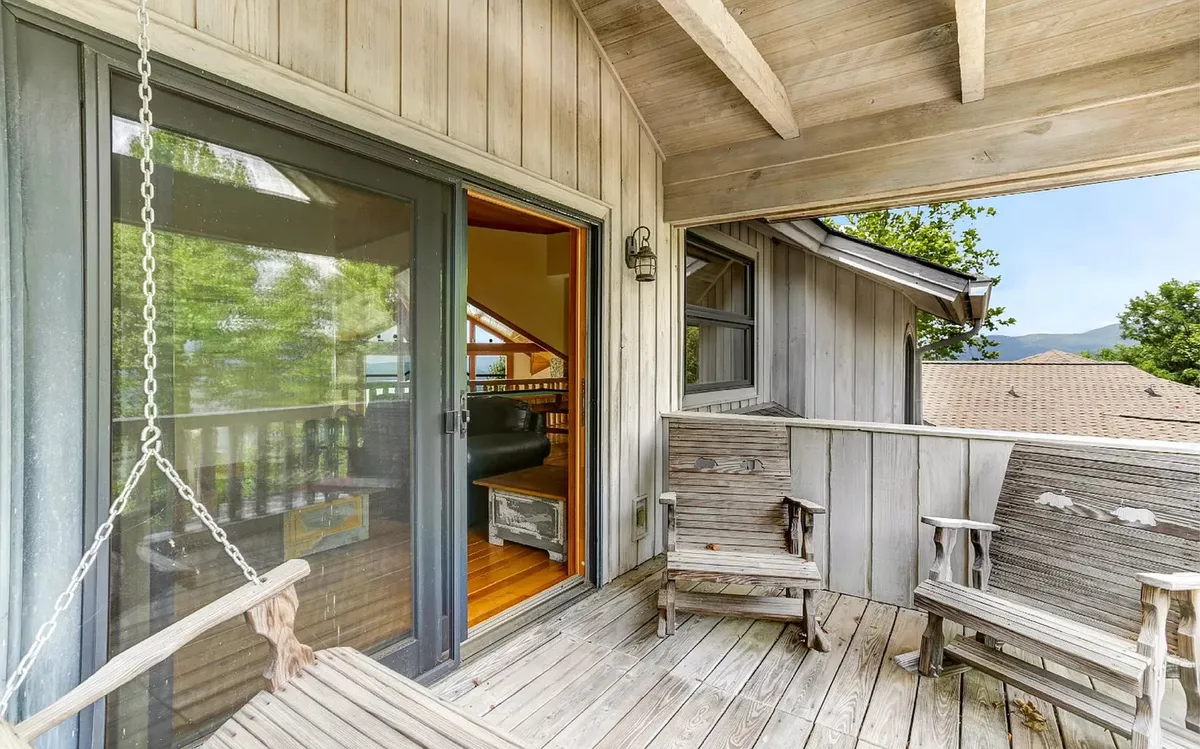 An exterior image capturing the romantic porch swing on the deck, surrounded by serene landscape views. This inviting outdoor nook suggests a seamless transition from the loft’s interior to the private deck, where guests can lounge, read, or watch the sunset.